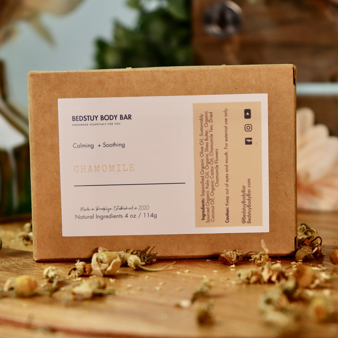 Brown cardboard box with a label on a wooden surface with dried flowers.