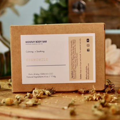 Brown cardboard box with a label on a wooden surface with dried flowers.