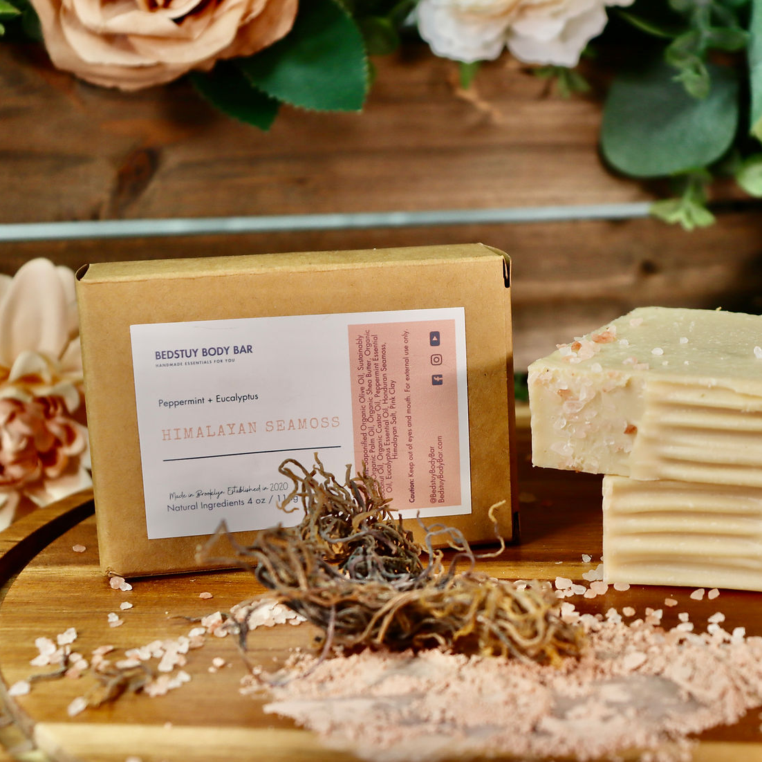 Two soap bars on a wooden surface with a box and decorative elements.