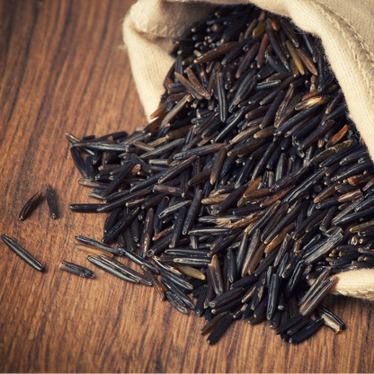 Wild rice spilling out of a beige bag on a wooden surface